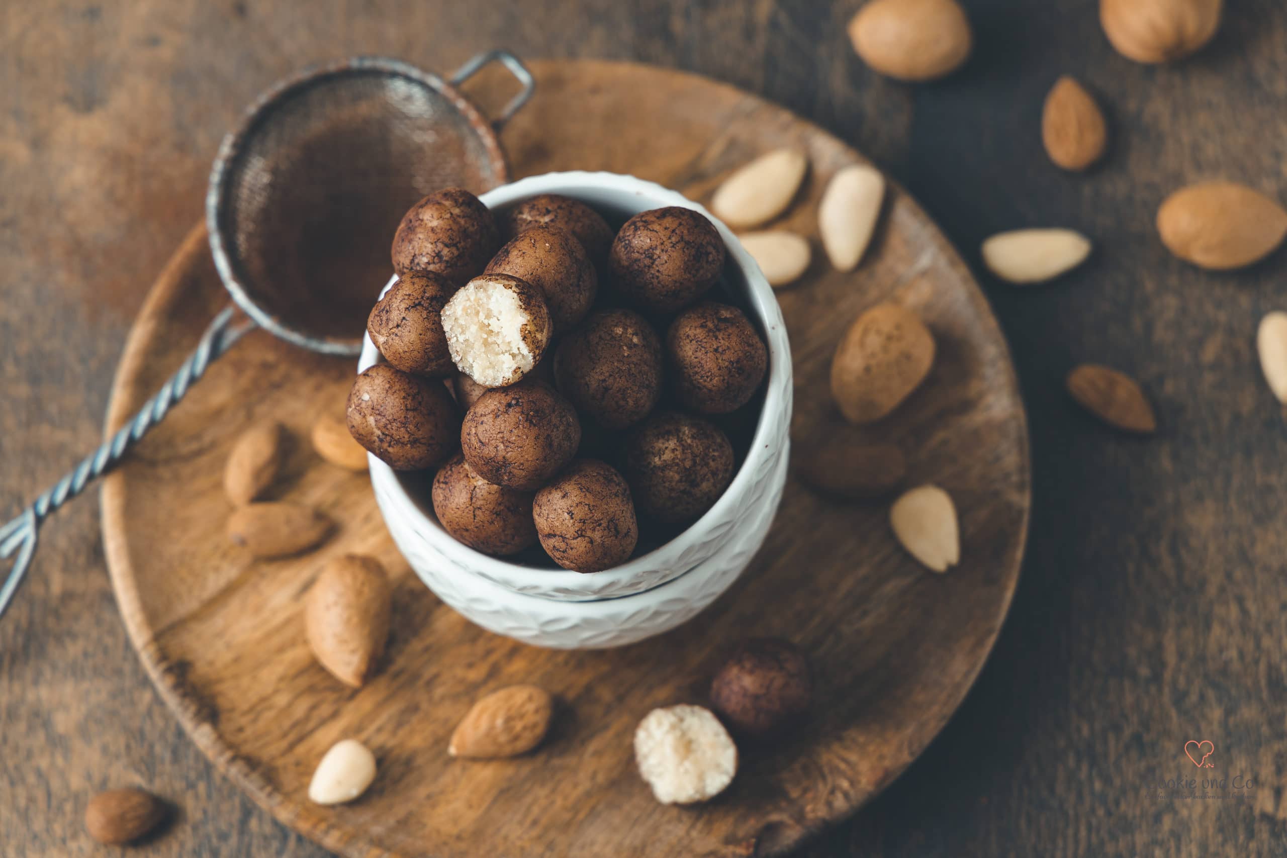 Marzipankartoffeln mit Mandeln und Amaretto im Hintergrund