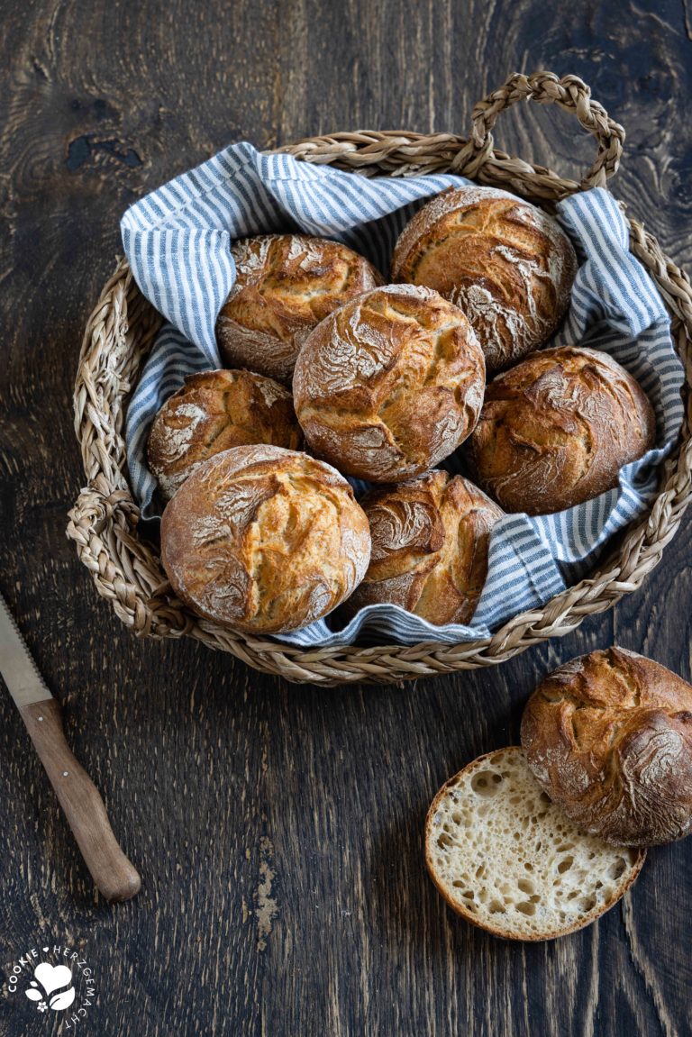 Rustikale Auffrischbrötchen mit Sauerteigresten in einem Brötchenkorb mit einem Blau gestreiften Tuch. Die Brötchen haben einer aromatische, lockere Krume und knusprige Kruste.