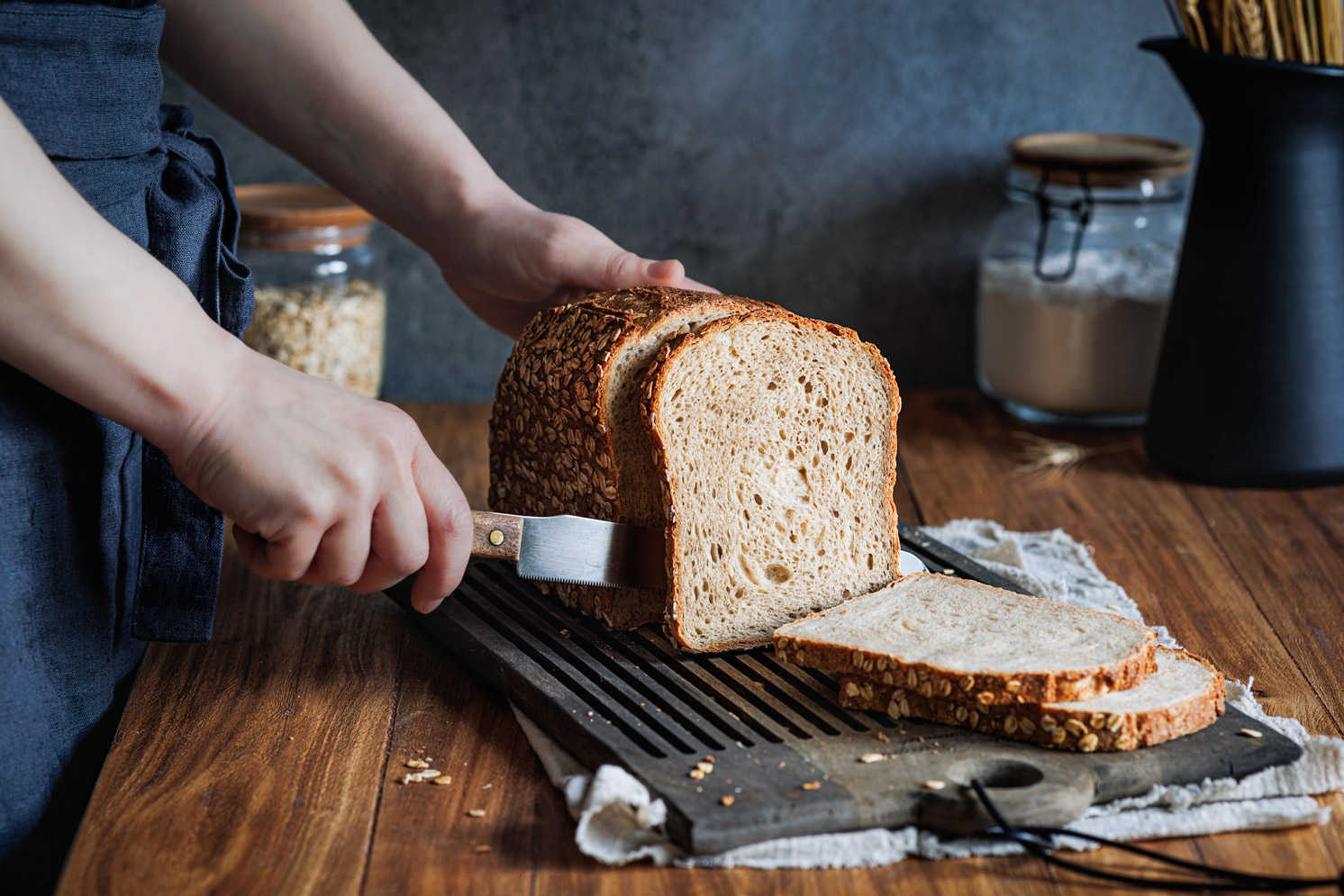 Hafer-Joghurt-Brot auf einem Holzbrett, das in Scheiben geschnitten wird.